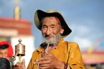 Elderly Tibetan man holding a prayer wheel